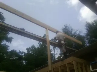 Carpenter setting a ridge beam over a new addition frame — Ice Dam Removal by Roofing Brothers in Hendrix