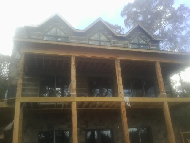 Dormers and porch framing on a large log home under construction — Roof Coating work by our crew in Hendrix