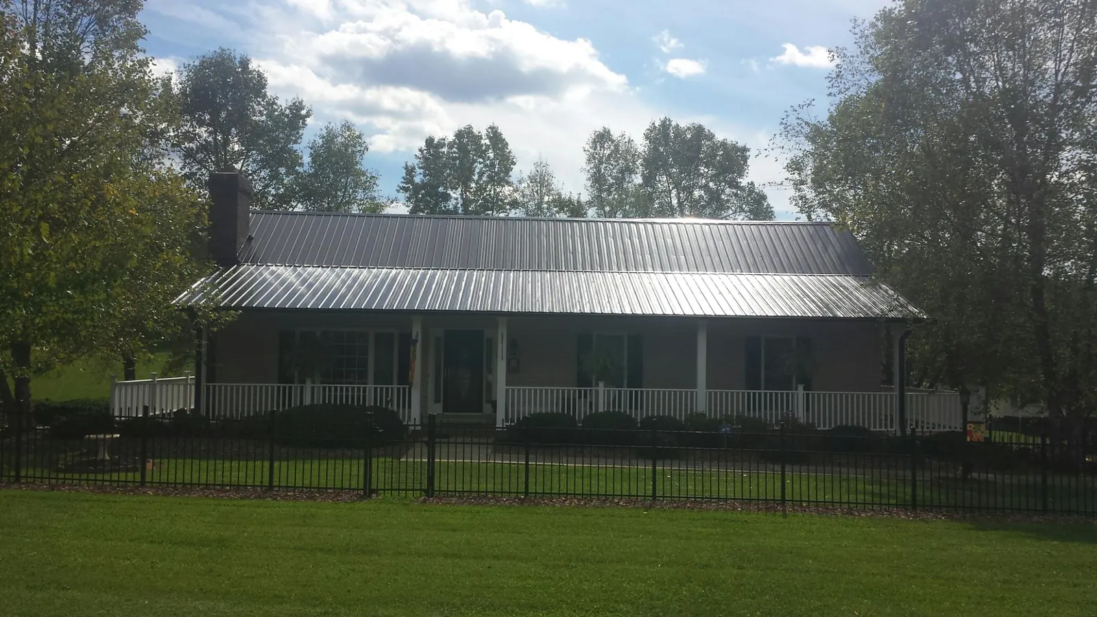 Gray metal roof on a brick ranch with a full width front porch — Gutter Guard Installation work by our crew in Hendrix