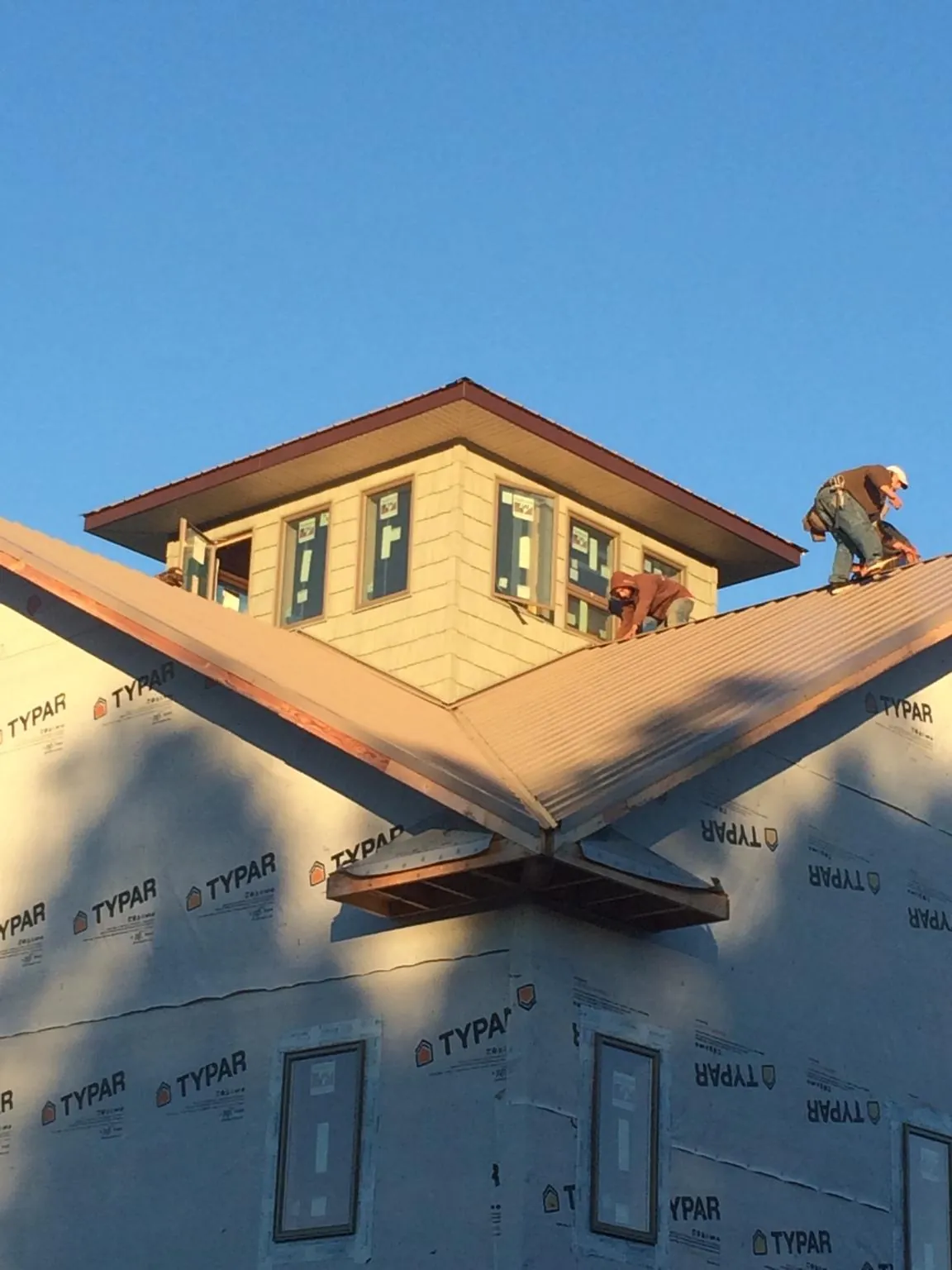 Roofers working around a rooftop cupola on a new metal roof at sunset — Roof Waterproofing in Hendrix by Roofing Brothers
